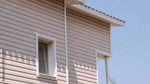 The facade of the new house clad with siding, with windows, against the blue sky.