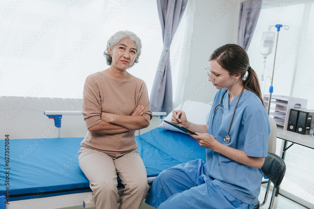 Fototapeta premium Young beautiful smiling doctor nurse caring to help happy senior grandmother helping old patients in rehabilitation at elderly health checkup