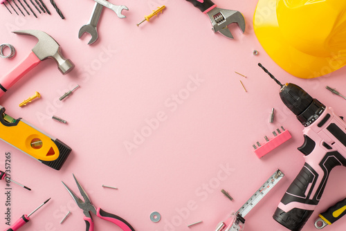 Recognizing the impact of female workers on Labor Day. Above view photograph featuring a pink backdrop, helmet and building tools, offering copyspace for adverts or text