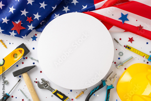 Happy Labor Day concept. Top view image of collection of different instruments for renovation with american flag and shiny confetti on white background with empty circle for greeting message