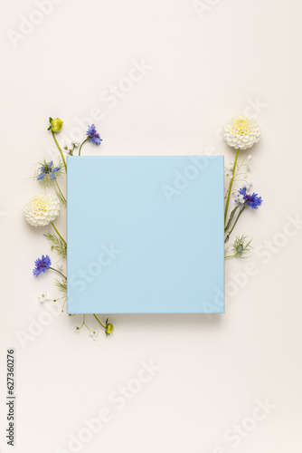 Paper card with border frame made of dahlia flower on a beige background. Springtime composition for 8 March with copyspace.