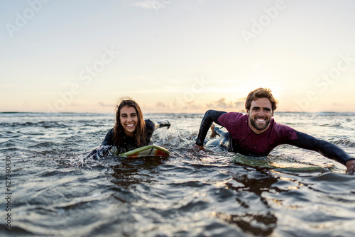 A happy surfers swimming with surfboard in the ocean.