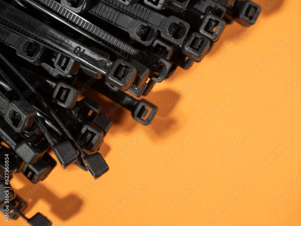 Plastic black ties on an orange background. Plastic ties for cables. Plastic black ties on an orange background. Plastic ties for cables.