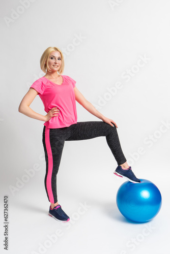 Woman in sportswear and sneakers goes in for sports with a fitness ball