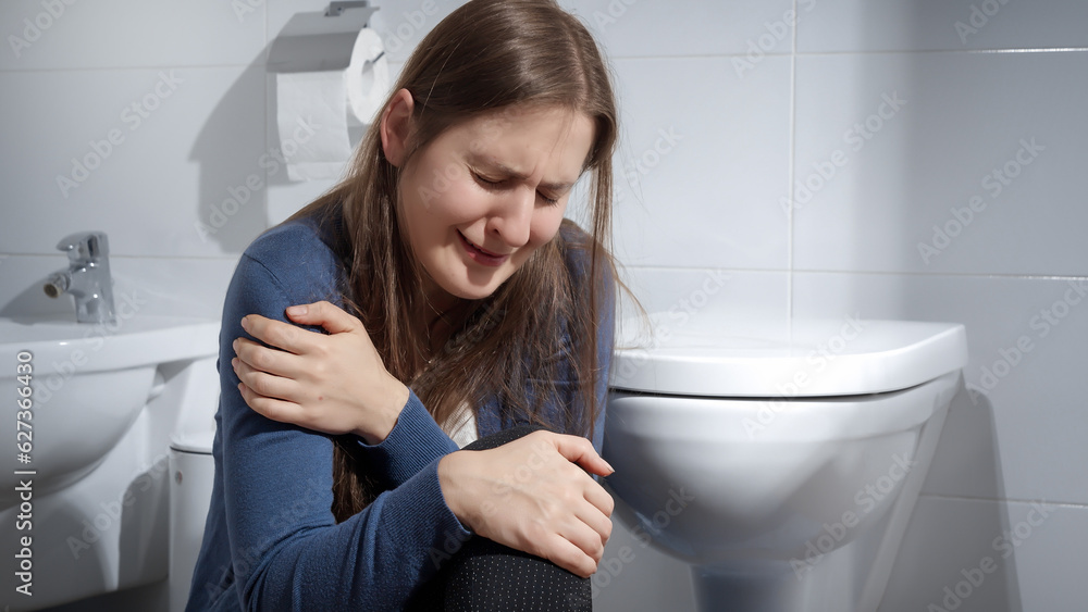 Lonely woman suffering from domestic violence crying on floor in toilet. Concept of depression, home violence, suicide, stress, loneliness and frustration. Lonely woman suffering from domestic violence crying on floor in toilet. Concept of depression, home violence, suicide, stress, loneliness and frustration.