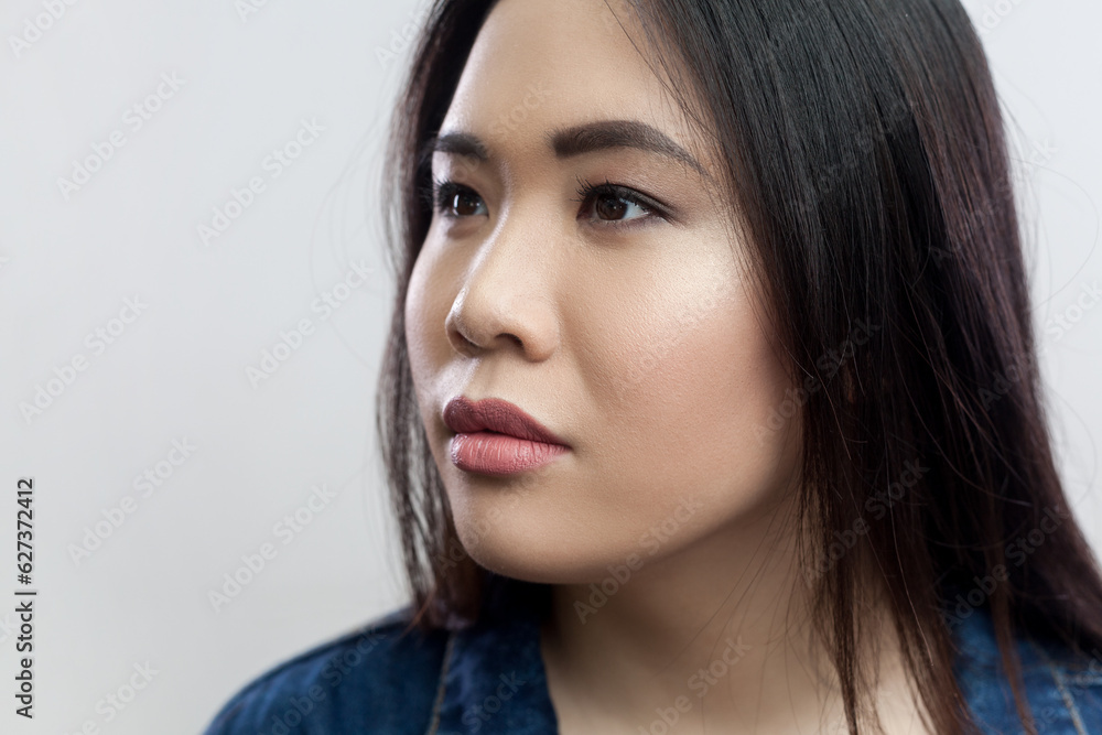Closeup portrait of pensive thoughtful attractive young adult brunette woman with beautiful makeup and long hair, looking away. Indoor studio shot isolated on gray background. Closeup portrait of pensive thoughtful attractive young adult brunette woman with beautiful makeup and long hair, looking away. Indoor studio shot isolated on gray background.