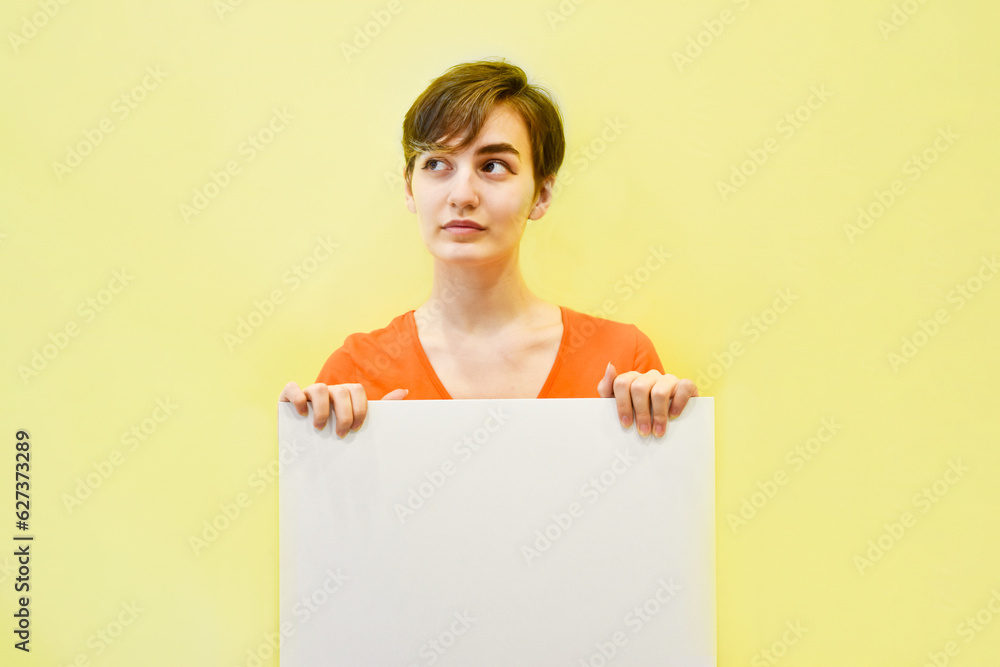 cute young woman is holding white blank form on background of yellow wall. Layout Template cute young woman is holding white blank form on background of yellow wall. Layout Template