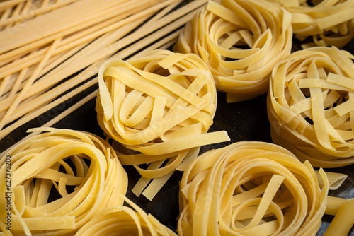 Pasta shapes, spaghetti and tagliatelle, italian cuisine ingredients on a wooden background