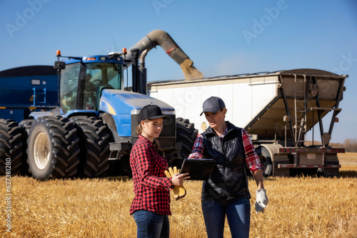 Woman farmer teaching apprentice advanced farming technologies during grain harvest, Alberta, Canada
