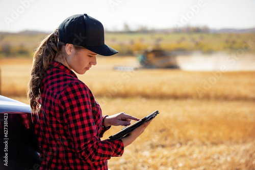 Young farm woman using advanced farming technologies during grain harvest, Alberta, Canada photo