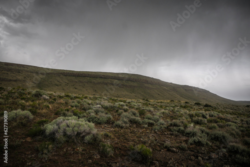 Sage brush desert below rolling mesas in desert terrain near Twin Falls Idaho with stormy skies