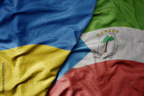 big waving national colorful flag of ukraine and national flag of equatorial guinea .