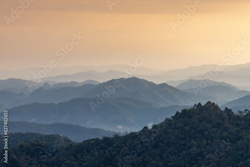 Scenic view of Mountain landscape with golden yellow sky in evening, Layer of big mountains and orange sky and misty during sunset, Majestic sunset in the mountains landscape, Nature background.