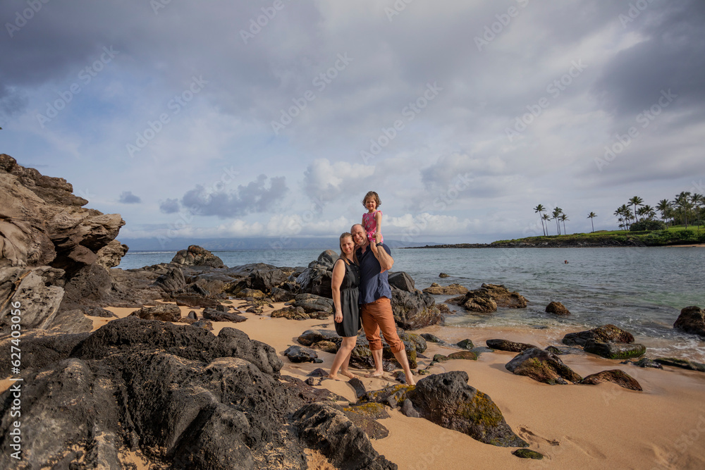 Family portrait, with father carrying daughter on shoulders, standing on the beach on vacation at Kaanapali in West Maui; Maui, Hawaii, United States of America