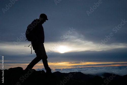 Silhouette of man hiking at Haleakala at sunrise over the Pacific, Maui, Hawaii, USA
