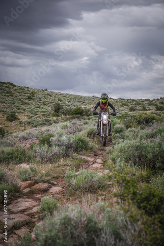 Female Dirt biker through sage brush desert terrain with stormy sky back drop near Twin Falls Idaho