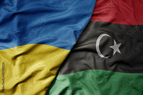 big waving national colorful flag of ukraine and national flag of libya .