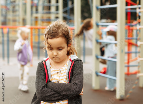 Upset lonely bullied little kid girl looking away feels abandoned abused, sad alone preschool child in kindergarten or playground