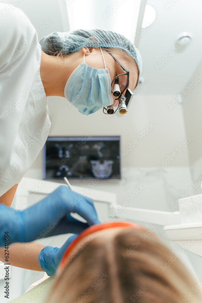 Low angle view of the female dentist holding equipment while examining woman patient Low angle view of the female dentist holding equipment while examining woman patient