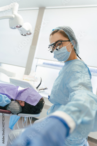 Professional dentist with microscope doing teeth checkup on patient