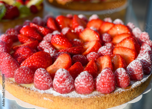 French fresh baked sweet pastry with fresh red summer fruits and berries in confectionery shop close up