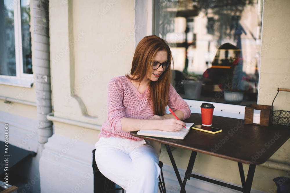 Focused woman writing in notebook in cafe Focused woman writing in notebook in cafe