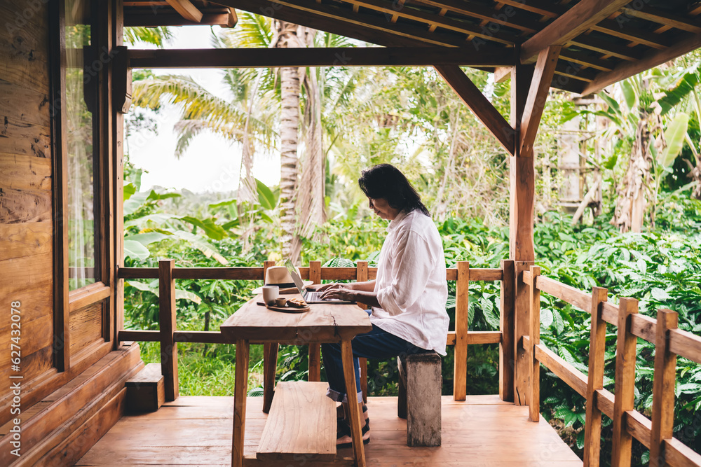 Ethnic man sitting at table and typing on laptop in terrace Ethnic man sitting at table and typing on laptop in terrace