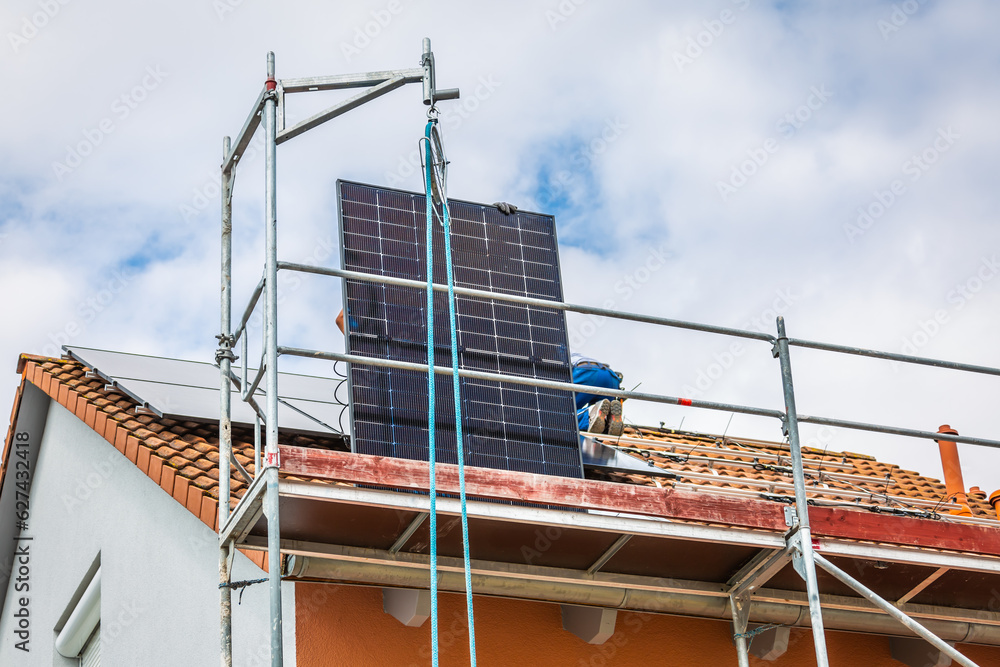 Lifting solar panels using pulley. Installing solar panels on a roof. Solar panels on roof.