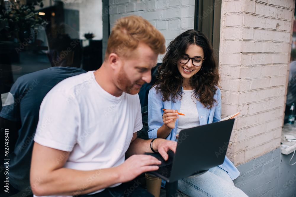 Fototapeta premium Caucasian IT professionals discussing web design during graphic projecting via laptop application, young male and female with digital netbook technology browsing information during together e learning