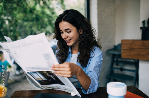 Foto Cheerful Caucasian female with smile on face spending time in street cafe readin