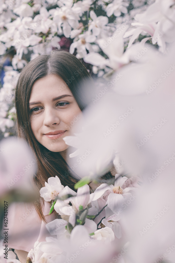 Closeup portrait of beautiful young woman in magnolia flowers. Spring girl with magnolia flowers. Portrait of brunette girl in pink dress. Closeup portrait of beautiful young woman in magnolia flowers. Spring girl with magnolia flowers. Portrait of brunette girl in pink dress.