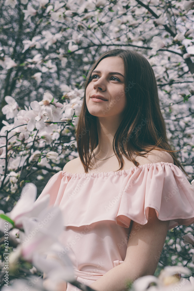 Portrait of beautiful young woman in magnolia flowers. Spring girl with magnolia flowers. Portrait of brunette girl in pink dress. Portrait of beautiful young woman in magnolia flowers. Spring girl with magnolia flowers. Portrait of brunette girl in pink dress.