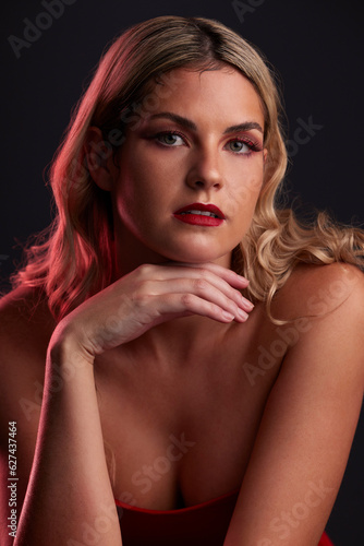 Portrait, face and beauty with a woman in studio on a dark background in red lighting for desire. Skincare, makeup or cosmetics with a young female model posing for natural feminine confidence