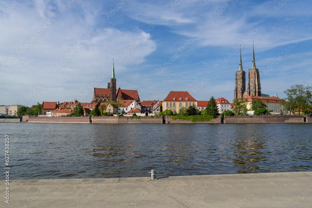 Obraz premium Outdoor view on the waterside of Oder river and background of Archbishop's Palace, Collegiate Church of the Holy Cross and St. Bartholomew and Wieża Katedry św. Jana Chrzciciela in Wroclaw, Poland.