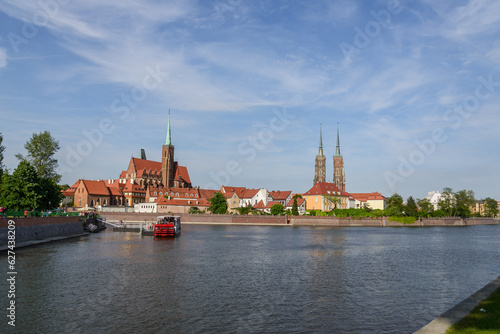 Outdoor view on the waterside of Oder river and background of Archbishop's Palace, Collegiate Church of the Holy Cross and St. Bartholomew and Wieża Katedry św. Jana Chrzciciela in Wroclaw, Poland. photo