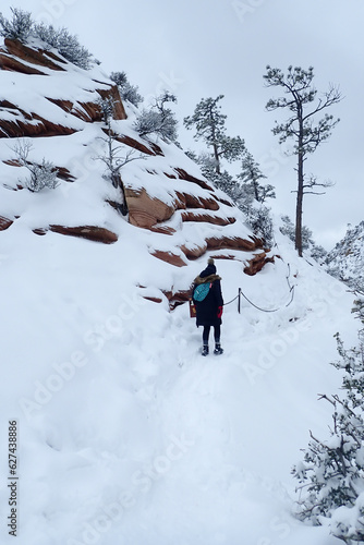 Hiker at the chains of Angel's Landing Trail in snow at Zion National Park, Utah