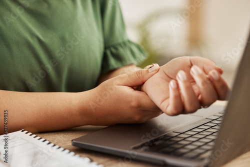 Closeup, laptop and woman with wrist pain, injury and overworked by desk, sprain hand or joint. Female person, entrepreneur or freelancer with a pc, carpal tunnel syndrome or ache with muscle tension photo