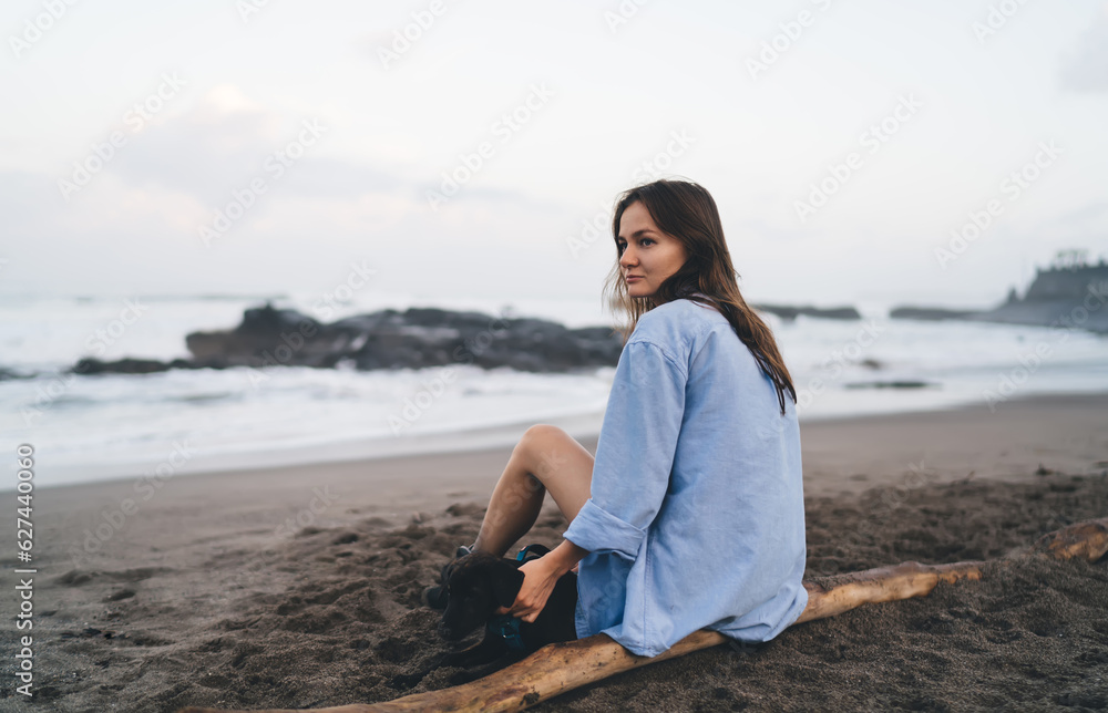 Young woman sitting and holding dog on beach