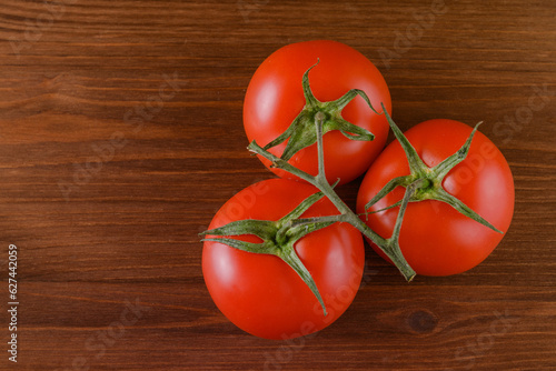 Fresh, ripe red tomatoes on wood background. Closeup of tomato branch. Top view