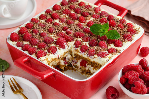 Raspberry tiramisu with chocolate in a red ceramic form. on pink background. Traditional Italian dessert. 