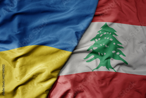 big waving national colorful flag of ukraine and national flag of lebanon . photo