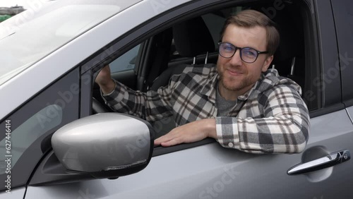 Man customer sitting in car salon and touching the steering wheel, choosing auto and wanting to buy new automobile in showroom dealership store. Car sales concept