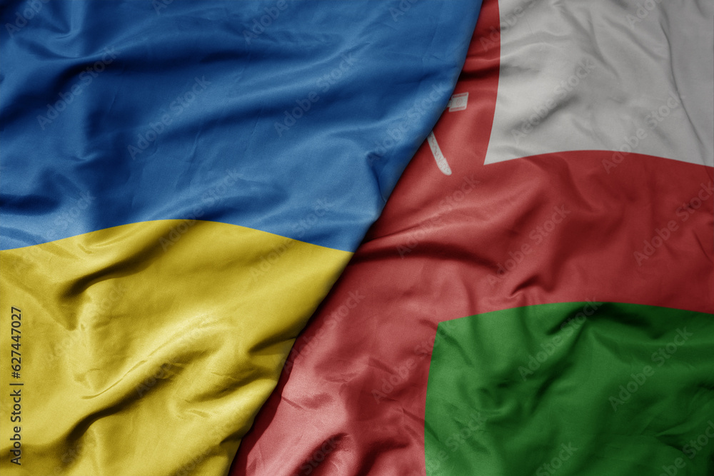 big waving national colorful flag of ukraine and national flag of oman .