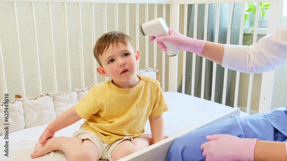 The nurse is checking the baby temperature with a contactless thermometer at home. Kid aged about two years (one year eleven months) The nurse is checking the baby temperature with a contactless thermometer at home. Kid aged about two years (one year eleven months)