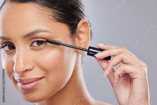 Portrait, mascara and woman with brush in studio for makeup, cosmetics and results on grey background. Eyelash, beauty and face of Indian female model with tool for treatment, application or volume