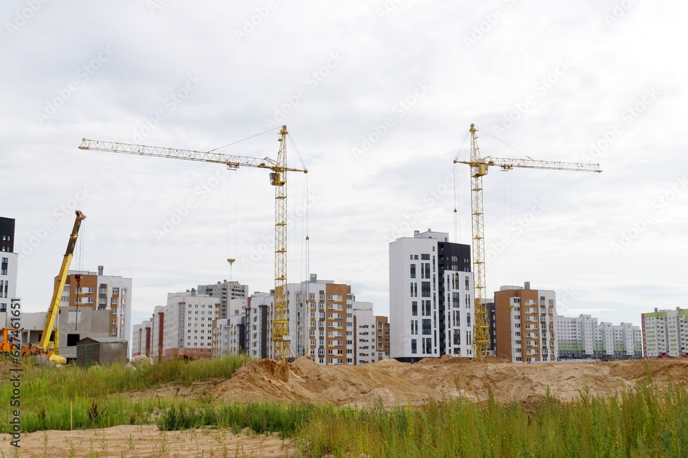 Tower cranes and a multistorey building under construction in a residential area. New modern residential apartment buildings.