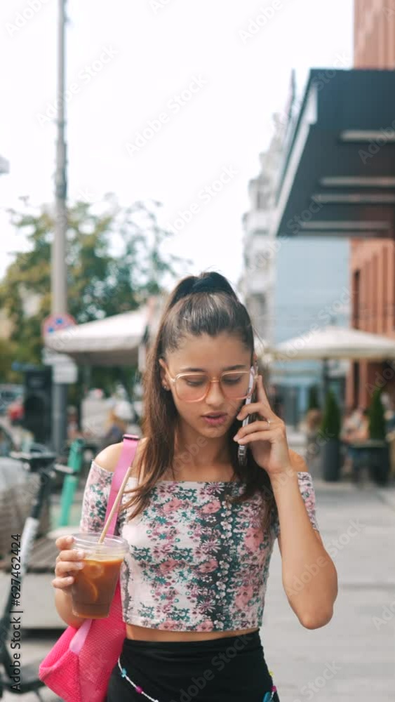 During rush hour, a vibrant young girl hurries down the street while talking on the phone. During rush hour, a vibrant young girl hurries down the street while talking on the phone.