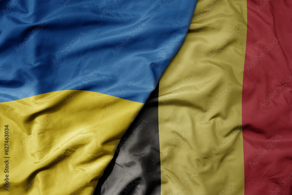 big waving national colorful flag of ukraine and national flag of belgium . big waving national colorful flag of ukraine and national flag of belgium .