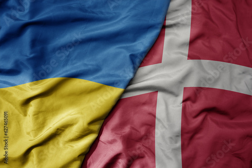 big waving national colorful flag of ukraine and national flag of denmark .