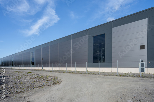 Exterior of a new and large grey warehouse.